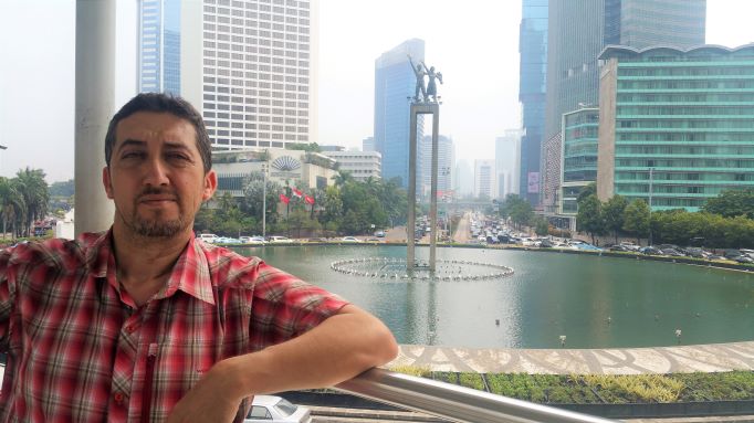 Larbi Megari pose devant un paysage urbain de Jakarta