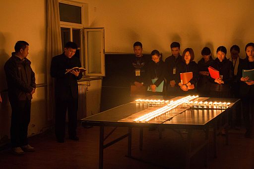 Personnes priant devant une croix de bougies dans une église de Pékin, Chine