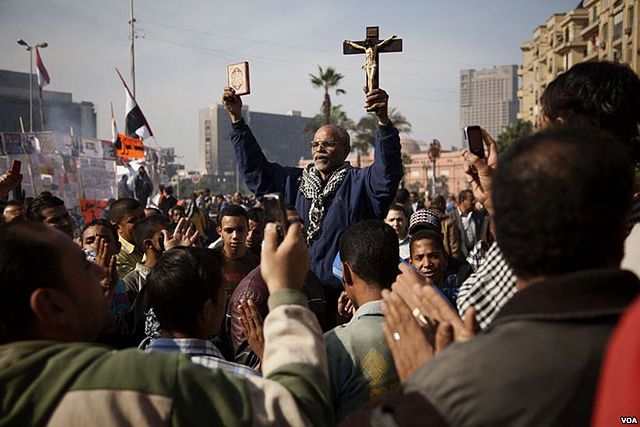A protester in Tahrir Square holds up a copy of the Quran and a Christian cross