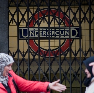 Two women with head coverings talking outside a shuddered London Underground entrace