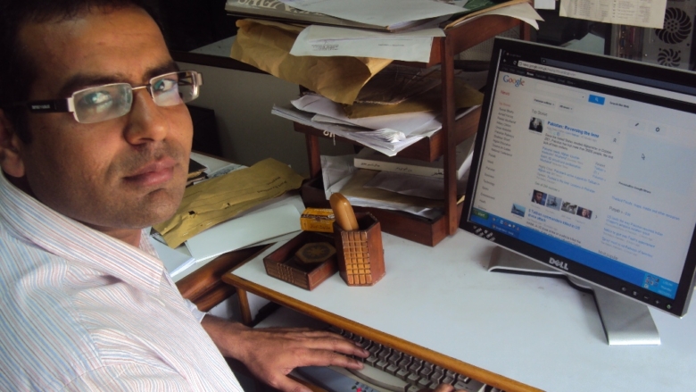 Waqar Gillani sentado ao computador com uma janela de navegação
